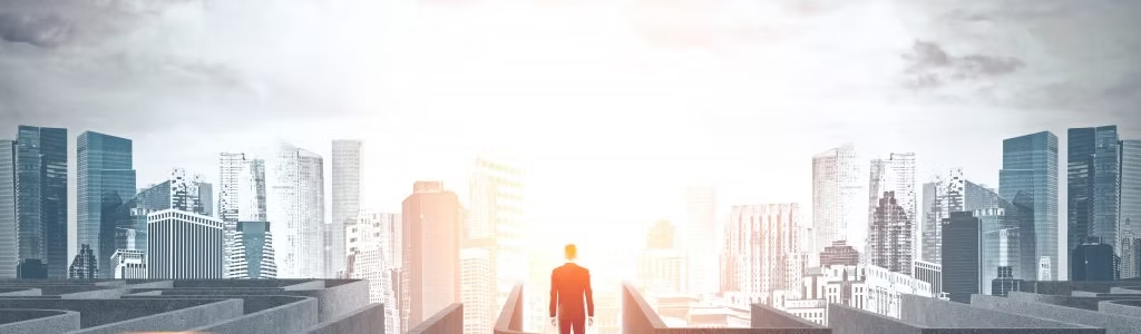 A businessman at the edge of a maze, facing the urban horizon
